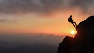 Sun setting on mountain climber sillhouette